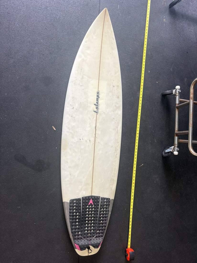 Stamps 5'10 surfboard deck, nose up, measuring tape on right